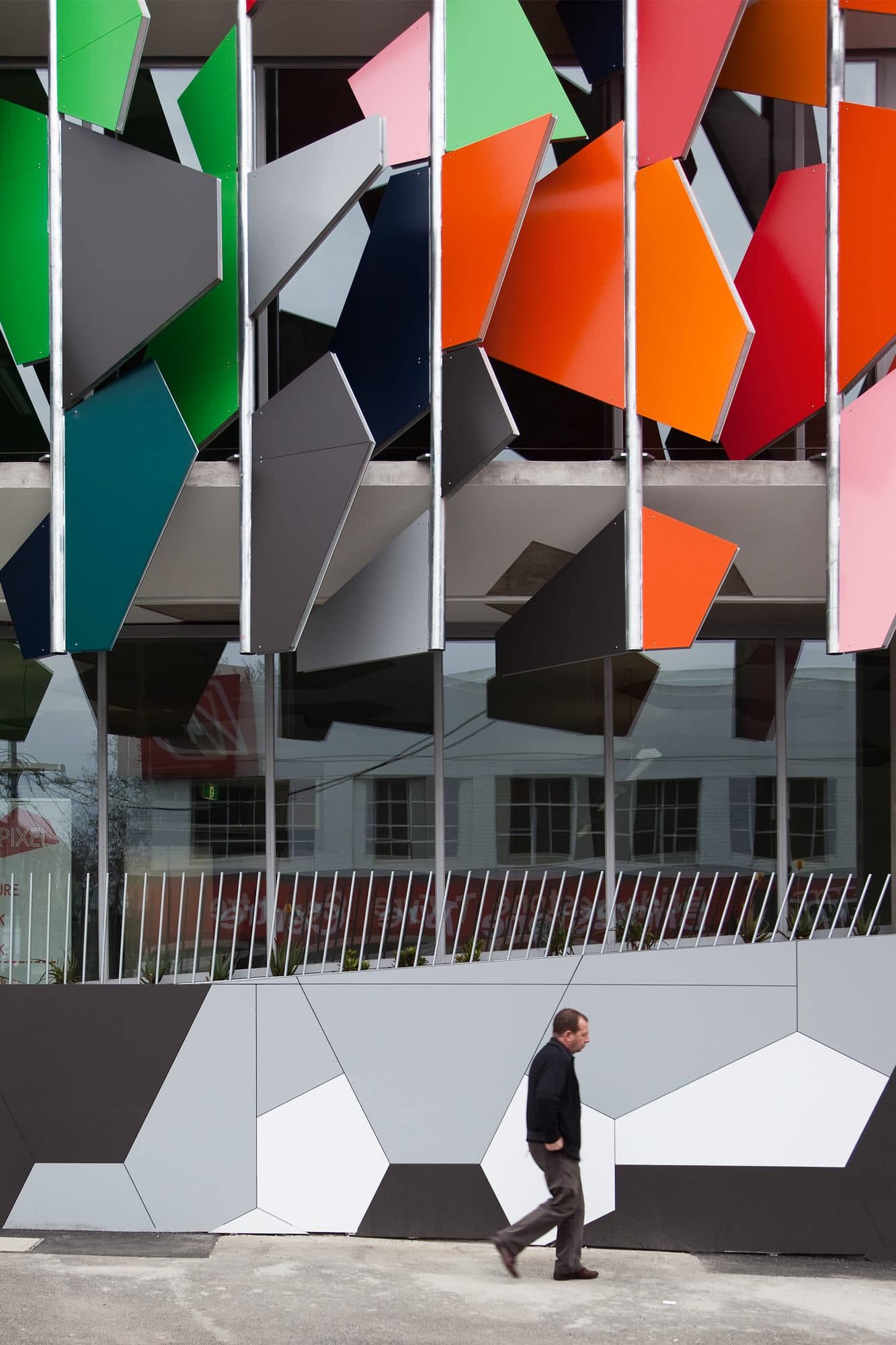 A man walks past the Pixel Building at street level.